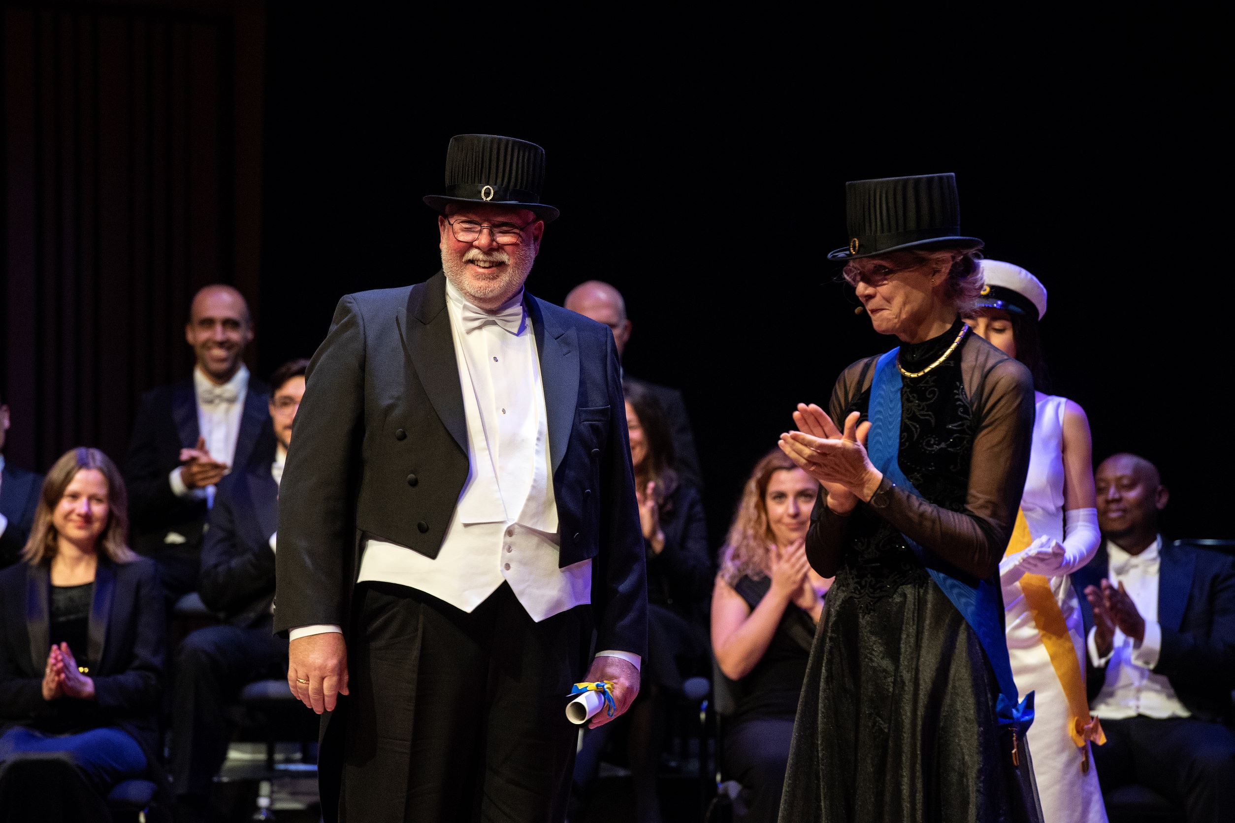 Man looking happy in a doctoral hat and festive clothes.